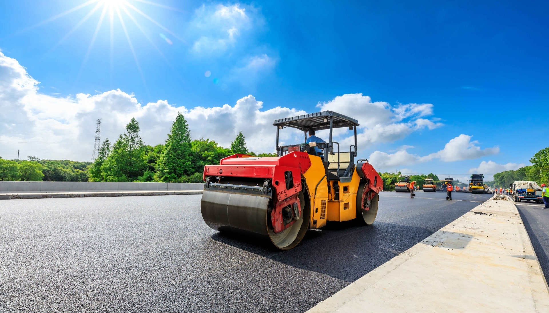 A team of construction workers operating heavy machinery, meticulously laying down fresh, smooth asphalt on a newly constructed road in Rochester, with steam rising from the hot surface.